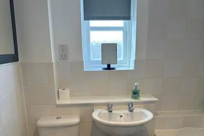 a bathroom with a toilet and a sink and a window at 2 Bed Apartment Sleeps 4 -Near Airport -WiFi & Tv in Renfrew
