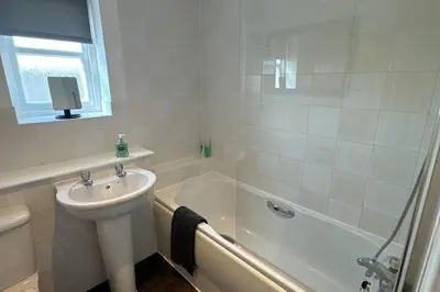 a white bathroom with a sink and a bath tub at 2 Bed Apartment Sleeps 4 -Near Airport -WiFi & Tv in Renfrew