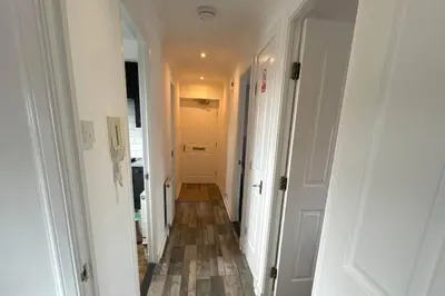 a hallway with white walls and a wooden floor at 2 Bed Apartment Sleeps 4 -Near Airport -WiFi & Tv in Renfrew
