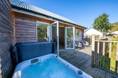 a hot tub on the deck of a house at Riverside Hideaway for Two Hot Tub River Lochay in Killin