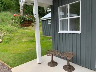 a couple of stools on a porch next to a house at The Tractor Shed- Elevated Hot Tub with Loch Views
