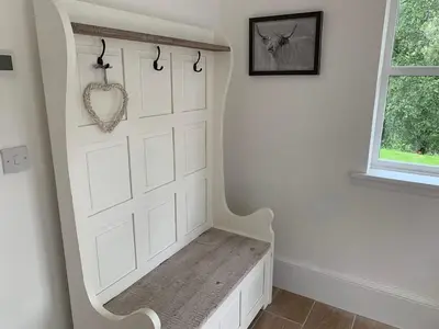 a room with a white door with a bench at The Tractor Shed- Elevated Hot Tub with Loch Views