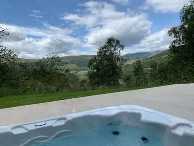 a bath tub with a view of the mountains at The Tractor Shed- Elevated Hot Tub with Loch Views