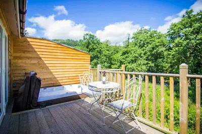a patio with a table and chairs on a deck at Garth Cottage - Riverside with Private Hot Tub in Killin