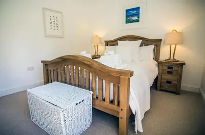 a bedroom with a wooden bed with white pillows at Garth Cottage - Riverside with Private Hot Tub in Killin