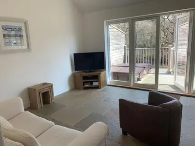 a living room with a couch and a tv at Garth Cottage - Riverside with Private Hot Tub in Killin