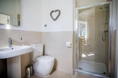 a bathroom with a toilet and a shower and a sink at Garth Cottage - Riverside with Private Hot Tub in Killin