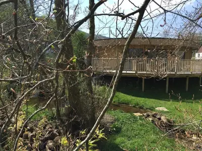 a house with a bridge over a creek at The Crannog Circular Riverside Retreat with Hot Tub in Killin
