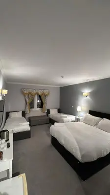 a hotel room with three beds and a television at Edinburgh West Residence in Edinburgh