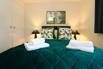 a bedroom with a green bed with towels on it at Signature Summerhill House in Bearsden
