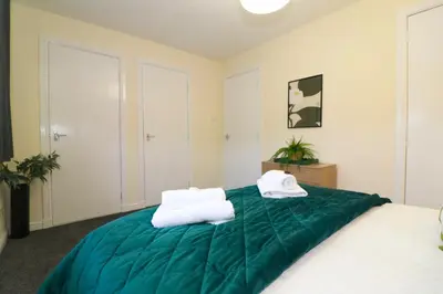 a bedroom with a green bed with towels on it at Signature Summerhill House in Bearsden