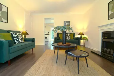 a living room with two green couches and a table at Signature Summerhill House in Bearsden