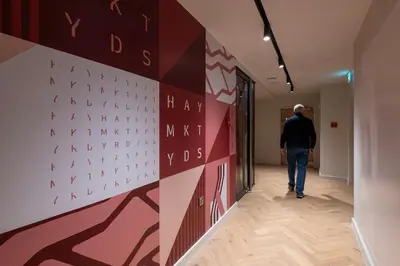 a man walking down a hallway with a wall with writing on it at For Students Only - Haymarket Yard in Edinburgh in Edinburgh