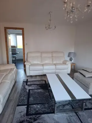 a living room with a white couch and a table at Cheerful 3 bedroom house with free parking in Hurlet