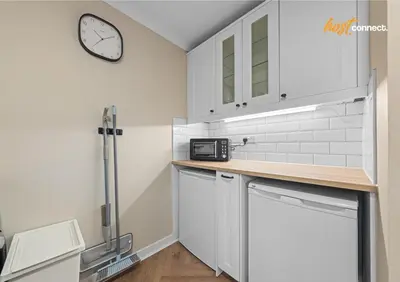 a kitchen with white cabinets and a clock on the wall at 2 Bed Home in Paisley I Sleeps 4 in Paisley