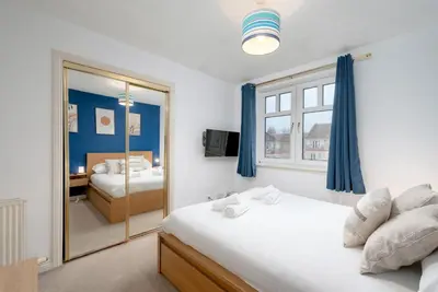 a bedroom with a bed and a mirror at Stylish 2-Bed Flat with Balcony Near Haymarket - Pass the Keys in Edinburgh