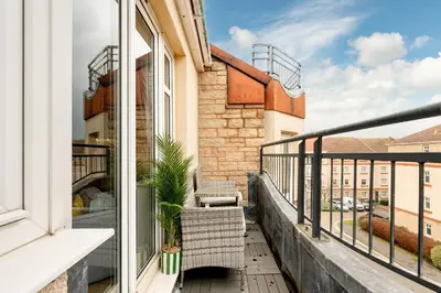 a balcony with two chairs and a window at Stylish 2-Bed Flat with Balcony Near Haymarket - Pass the Keys in Edinburgh
