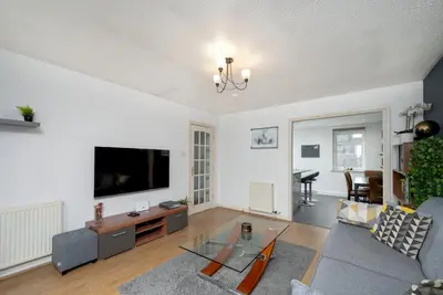 a living room with a couch and a tv at Stylish 2-Bed Flat with Balcony Near Haymarket - Pass the Keys in Edinburgh