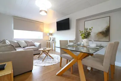 a living room with a table and a couch at Signature Greenfield House in Wishaw
