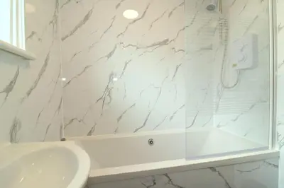 a white bathroom with a white tub and a sink at Signature Greenfield House in Wishaw