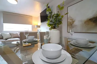 a dining room with a glass table with a vase at Signature Greenfield House in Wishaw