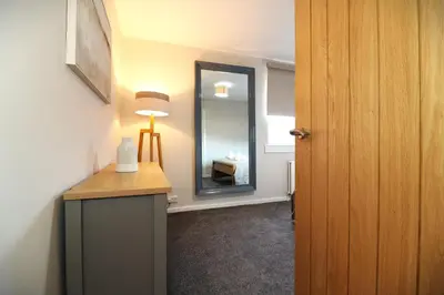a room with a mirror and a table with a lamp at Signature Greenfield House in Wishaw