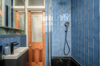 a blue tiled bathroom with a shower and a sink at Quiet 1-Bed Flat by the Meadows in Edinburgh