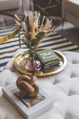 a table with a plate with a vase of flowers and a book at Luxury MArylebone Village family home in Moffat