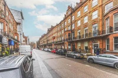 a city street with cars parked in front of buildings at Luxury MArylebone Village family home in Moffat