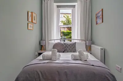 a bedroom with a bed with pillows and a window at Stylish 2-Bed Villa Garden Central Edinburgh in Edinburgh