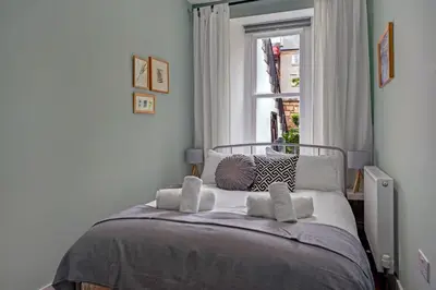 a bedroom with a bed with pillows and a window at Stylish 2-Bed Villa Garden Central Edinburgh in Edinburgh