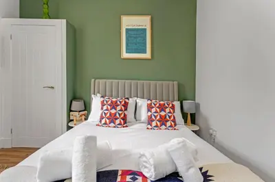 a bedroom with a large bed with green walls at Stylish 2-Bed Villa Garden Central Edinburgh in Edinburgh