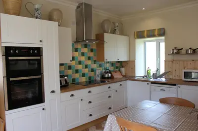 a kitchen with white cabinets and a table in it at Clachandubh Cottage in Lochgilphead