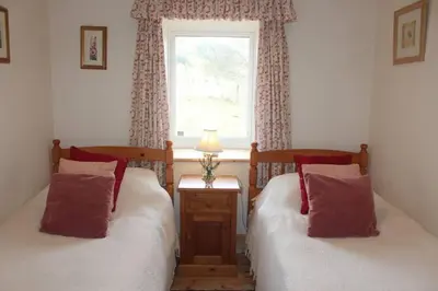 two twin beds in a room with a window at Clachandubh Cottage in Lochgilphead