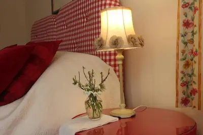 a lamp and a table with a vase of flowers on a bed at Clachandubh Cottage in Lochgilphead