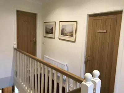 a hallway with two wooden doors and a staircase at Ederline Farm Cottage in Lochgilphead