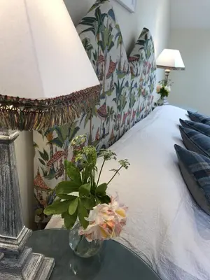 a vase with flowers on a table next to a bed at Ederline Farm Cottage in Lochgilphead