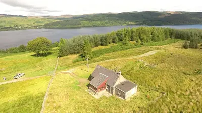 an aerial view of a house on a hill with a lake at Finchairn Cottage in Lochgilphead