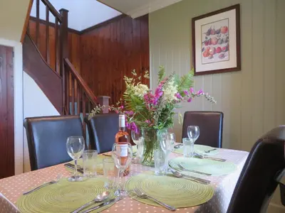 a table with a bottle of wine and flowers on it at Finchairn Cottage in Lochgilphead