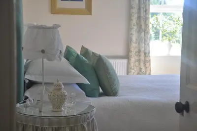a bed with a table with a lamp on it at Finchairn Farmhouse in Lochgilphead