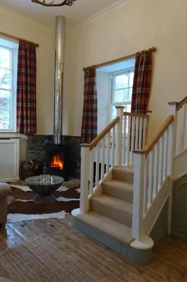 a living room with a staircase and a fireplace at School Room in Lochgilphead