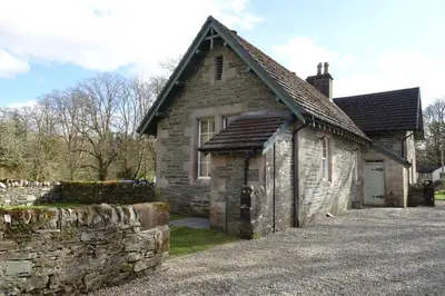 a stone house with a stone wall next to a driveway at School Room in Lochgilphead
