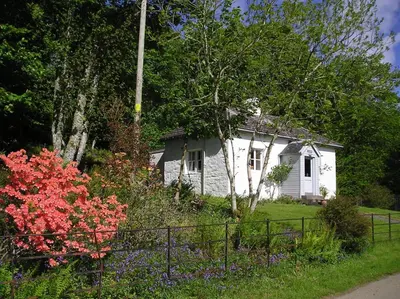 a small white house with flowers in front of it at South Lodge in Lochgilphead