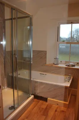 a bathroom with a shower and a tub with a window at The School House in Lochgilphead