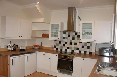 a kitchen with white cabinets and black and white tiles at The School House in Lochgilphead