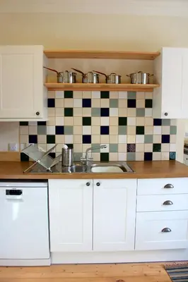 a kitchen with white cabinets and a sink at The School House in Lochgilphead