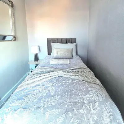 a bedroom with a bed with a blue and white blanket at Bright and Cozy 3BR Home Near Hampden Park in Glasgow