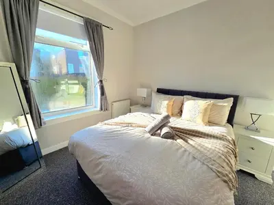 a bedroom with a large bed and a window at Bright and Cozy 3BR Home Near Hampden Park in Glasgow