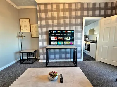 a living room with a table and a kitchen at Bright and Cozy 3BR Home Near Hampden Park in Glasgow