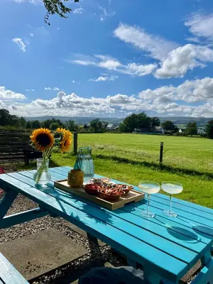 a blue picnic table with a plate of food and glasses at The Dome at Midauchengowan in Lochwinnoch